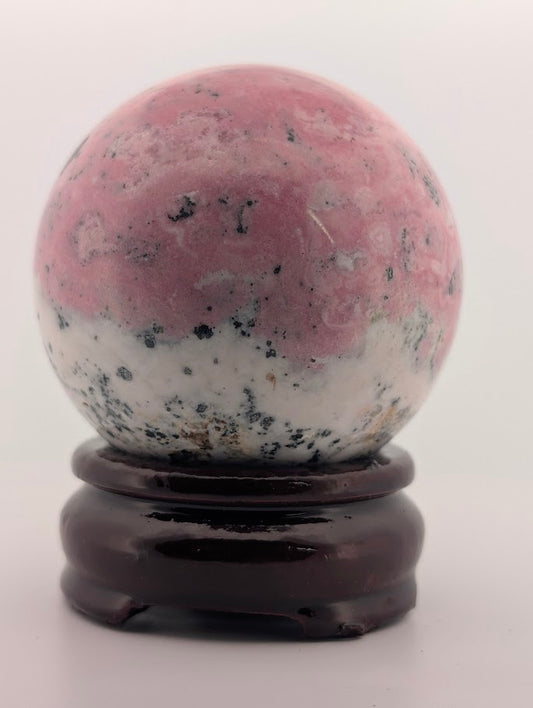 Polished rhodonite sphere side angle with manganese inclusions