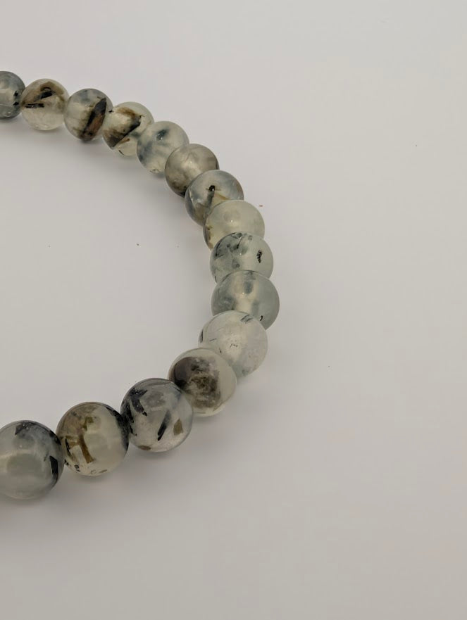 Closeup of 6mm Prehnite bracelet showing polished beads and natural inclusions.