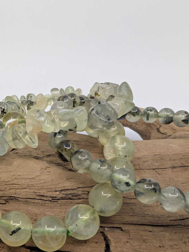 Close macro of Prehnite beads showing translucent green and black epidote needles.