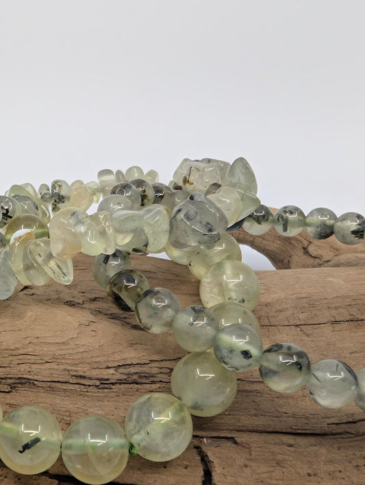 Close macro of Prehnite beads showing translucent green and black epidote needles.
