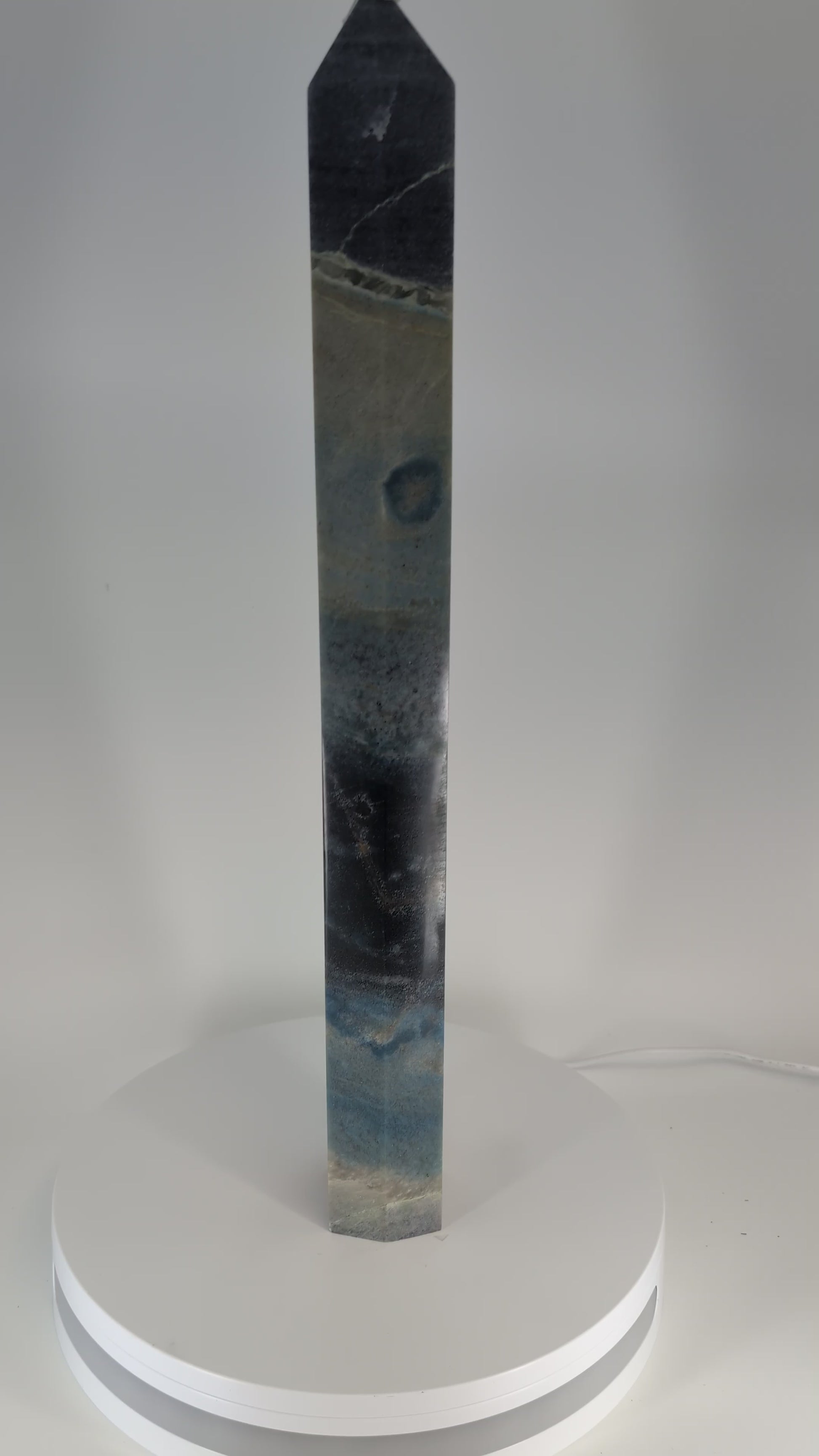 360-degree video of Trollite Tower TR-01 — a 17-inch (43 cm) polished blue-green crystal tower from Minas Gerais, Brazil, showing its gradient color zoning, reflective finish, and mica shimmer in natural light.