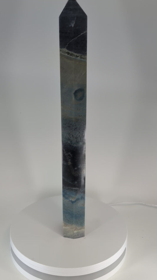 360-degree video of Trollite Tower TR-01 — a 17-inch (43 cm) polished blue-green crystal tower from Minas Gerais, Brazil, showing its gradient color zoning, reflective finish, and mica shimmer in natural light.
