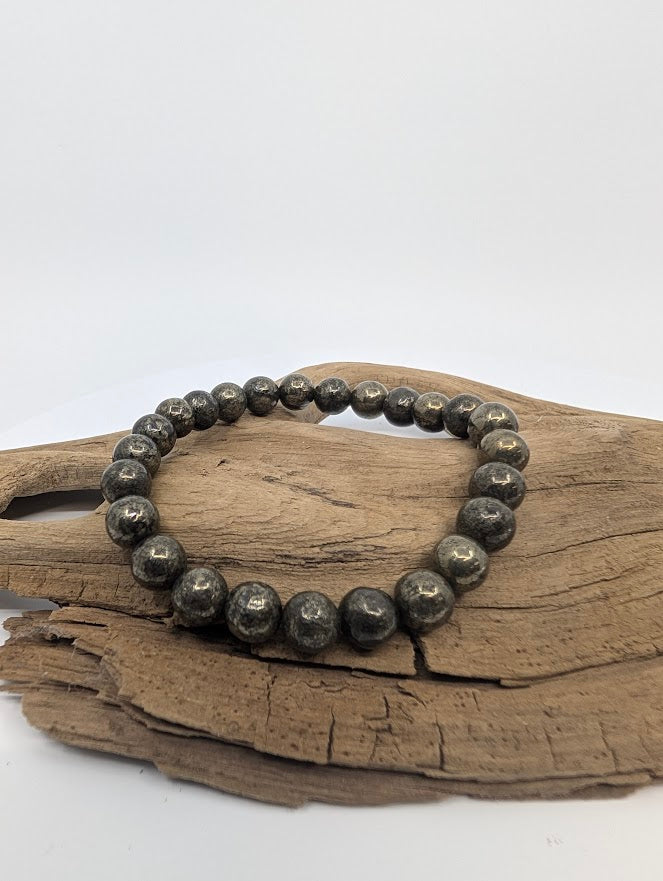 8mm pyrite bracelet with metallic gold sheen displayed on driftwood