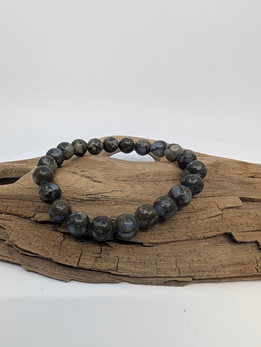 Que Sera 8mm round bead stretch bracelet on driftwood showing grey-blue marbling