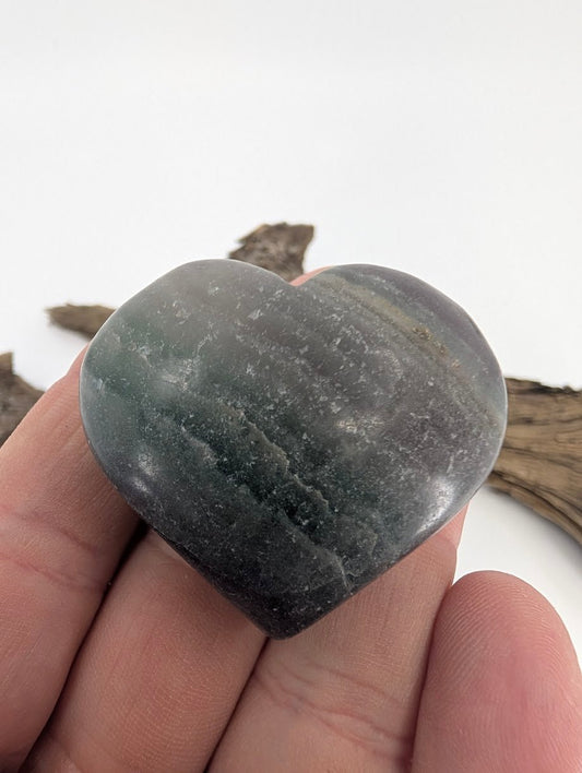 Hand holding a 70g Rainbow Fluorite heart to show size and polish.