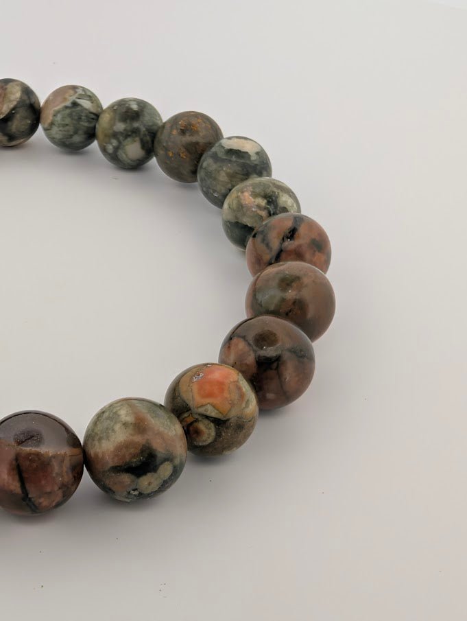 Detail of rainforest jasper bracelet highlighting green rhyolite matrix and warm accents