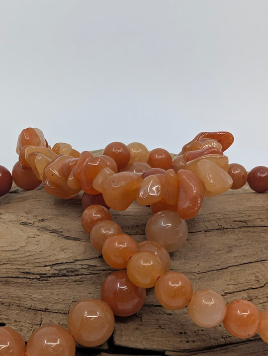 Closeup of chip and round red aventurine beads with warm orange-red tones