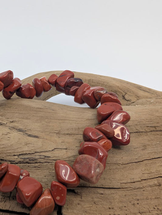 Closeup of polished red jasper chip bracelet showing natural matrix patterns