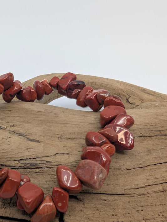 Closeup of polished red jasper chip bracelet showing natural matrix patterns
