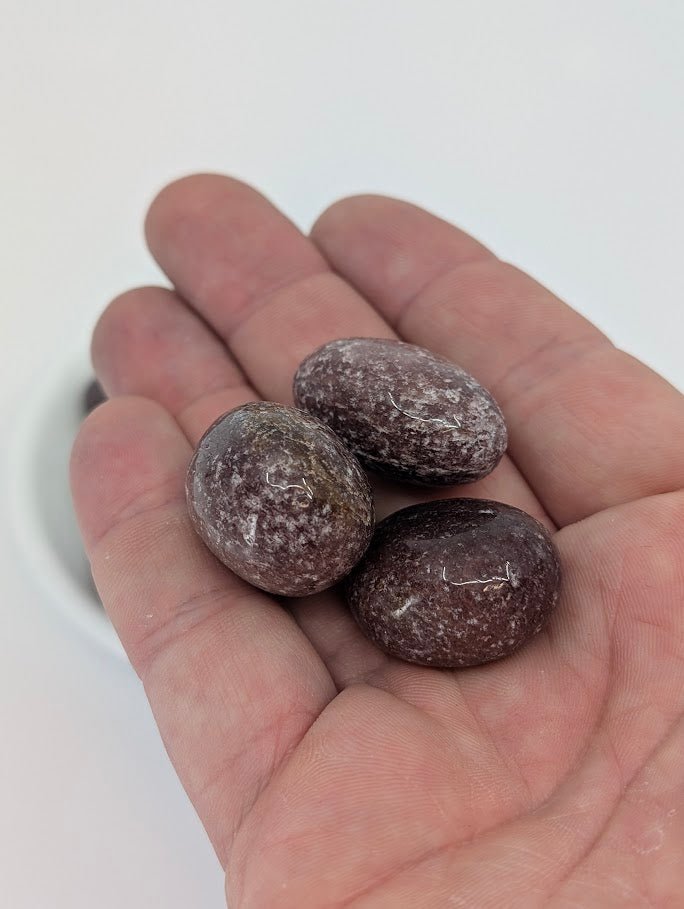 Red Strawberry Quartz tumbled stones in hand for size reference
