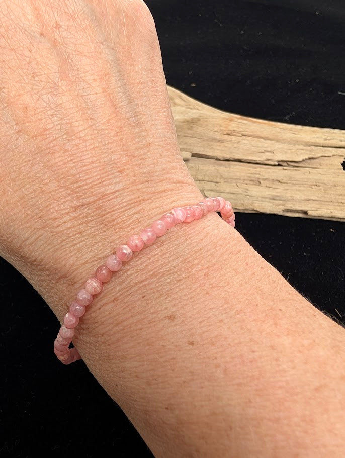 4mm AA-grade polished Rhodochrosite beaded stretch bracelet worn on a wrist for delicate size scale.