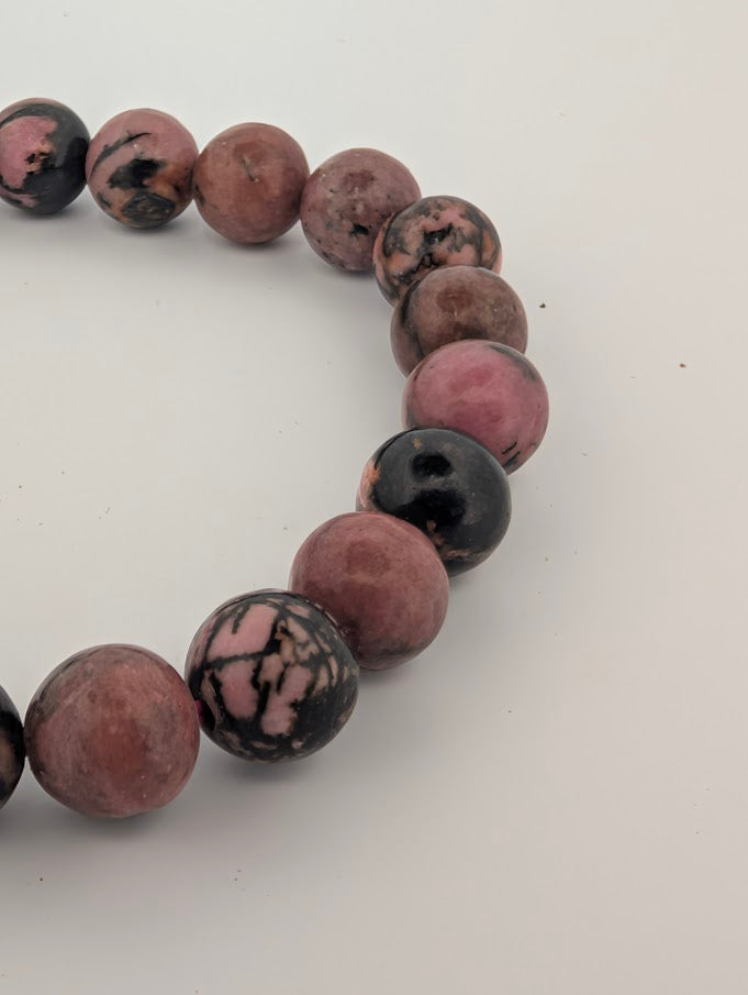 Close detail of 8mm rhodonite beads showing polished finish and natural veining