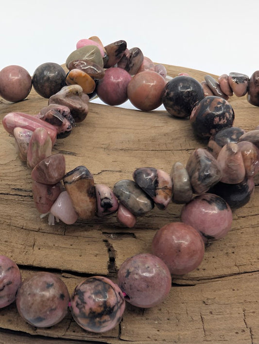 Closeup of rhodonite beads and chips highlighting pink color and dark veining