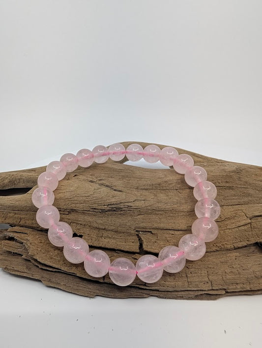 8mm rose quartz bracelet with soft blush beads displayed on driftwood