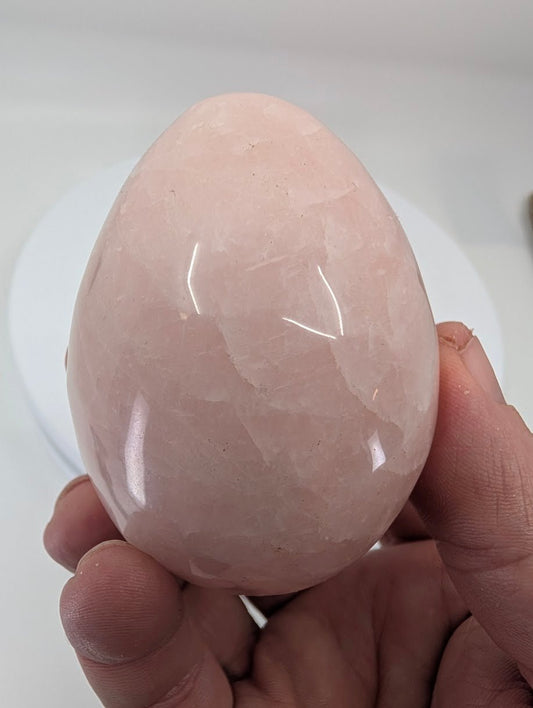Hand-held rose quartz egg highlighting natural pink tones and organic internal patterning