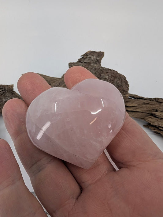 Hand holding a 75g puffy Rose Quartz heart showing size and glossy polish.