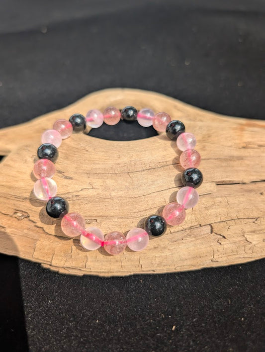 8mm Rose Quartz, Strawberry Quartz, and Obsidian beaded bracelet resting on driftwood display.