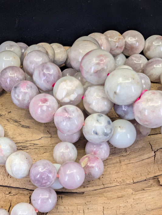 Macro view of high-quality Rubellite in Lepidolite beads, highlighting the vibrant pink mineral pockets and shimmering silvery-grey mica matrix.