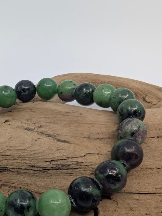 Closeup of polished 8mm ruby in zoisite beads showing pink ruby and dark veining