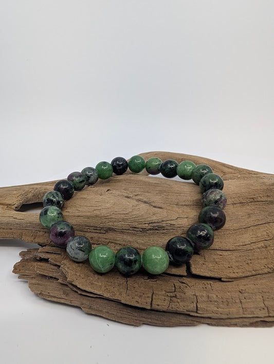 Ruby in zoisite bracelet with green matrix and ruby spots displayed on driftwood