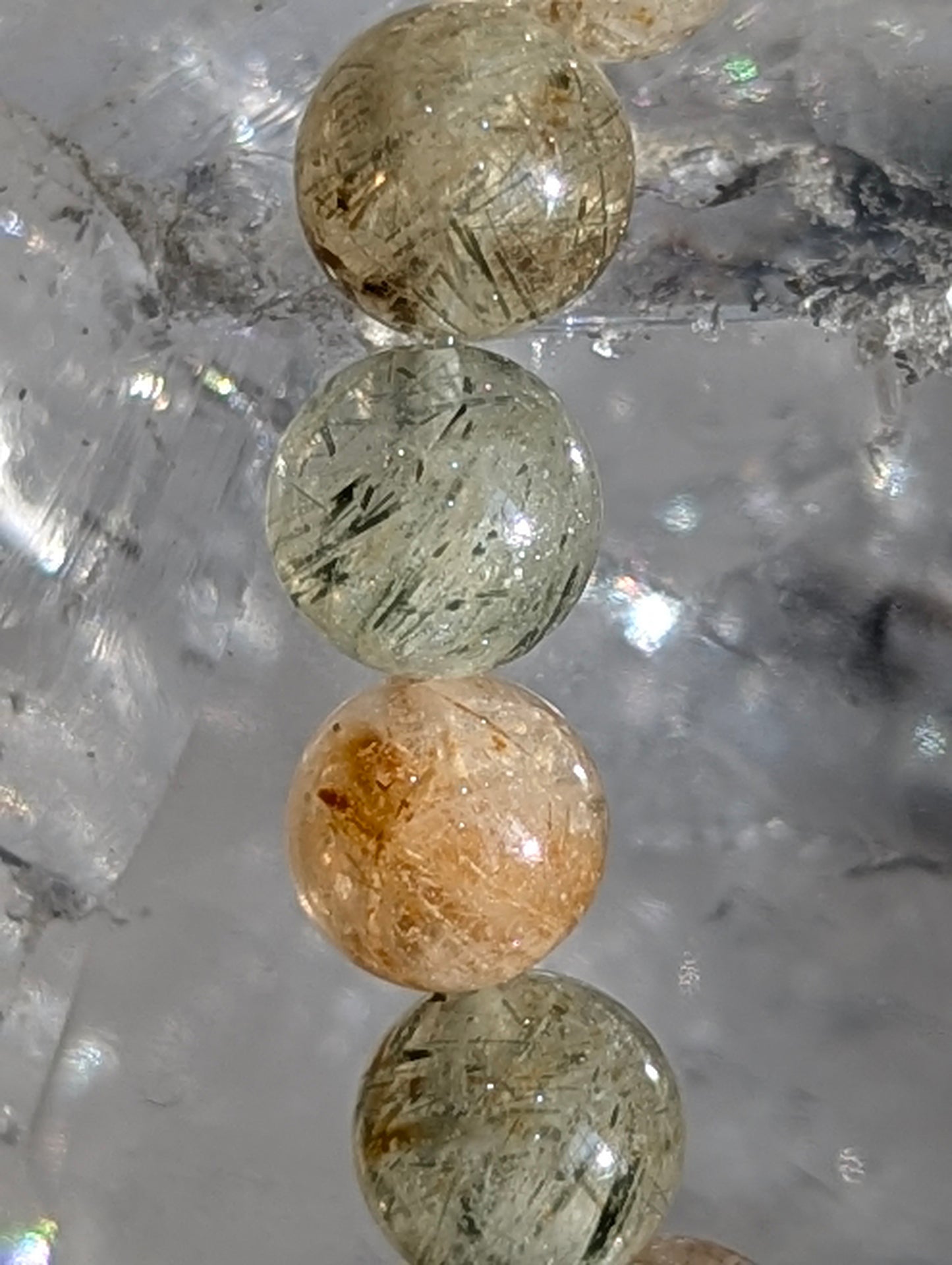 Macro detail of individual 7mm beads showing needle-like rutile inclusions and quartz transparency.
