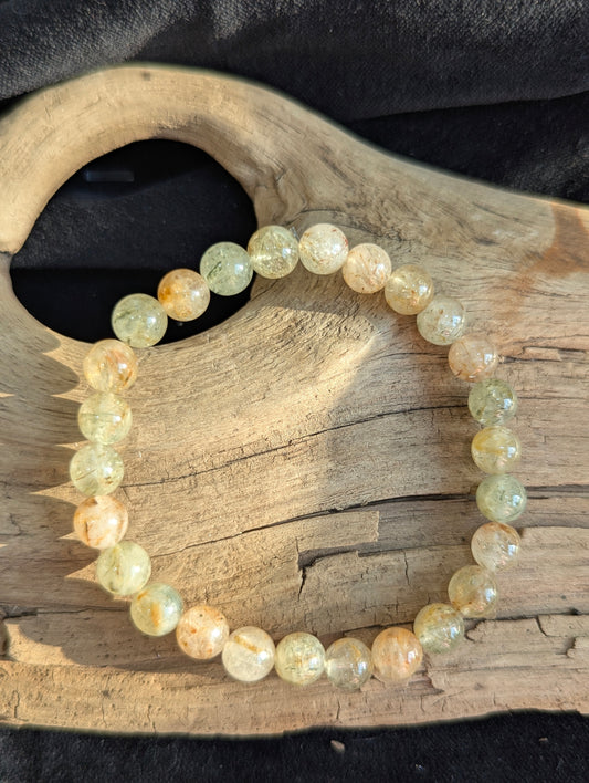 Single 7mm Rutilated Quartz bracelet on textured driftwood surface.