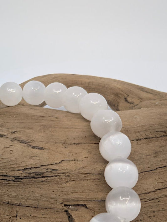 Close-up of polished 8MM Selenite bracelet beads with luminous glow
