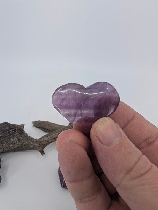 Fingers holding a small 25g Fluorite heart to show petite size.