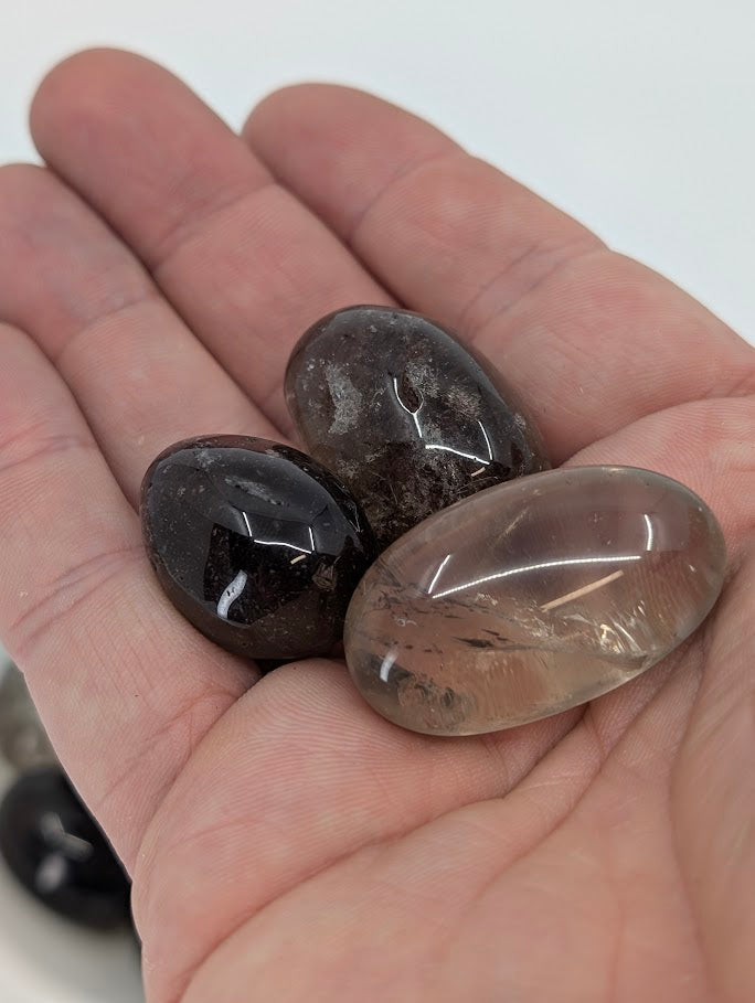 Smoky Quartz tumbled stones shown in hand for scale