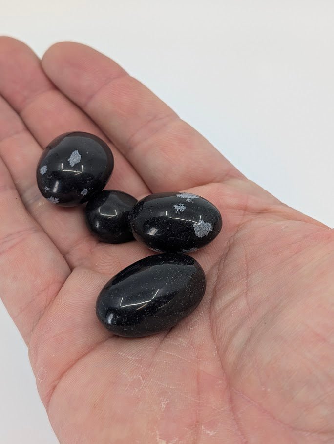 Snowflake Obsidian tumbled stones in hand for size reference