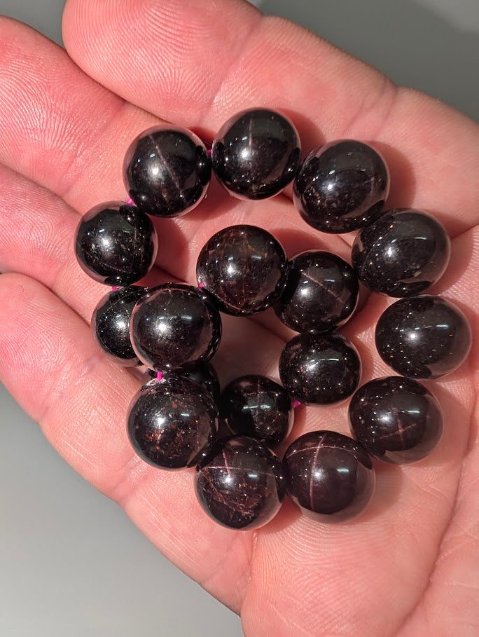 Star flash garnet bracelet held in light showing red star reflections