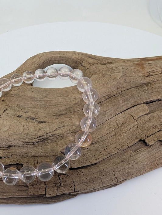 Close-up of 8mm Rose Quartz beads highlighting the internal "whisper-pink" veils and silky textures.