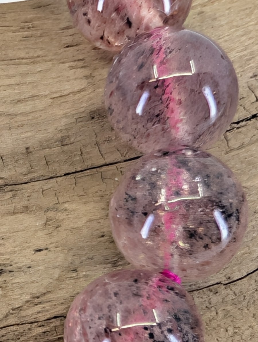 Macro view of Strawberry Quartz beads showing the sparkling hematoid fire and professional vitreous luster.