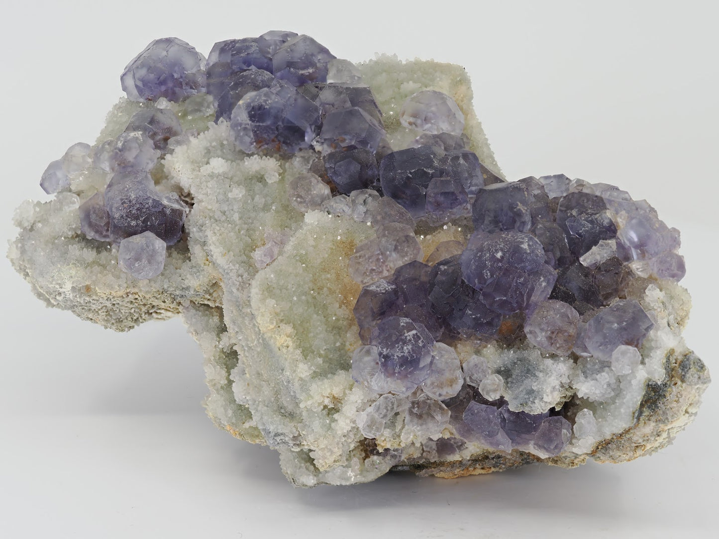 Cabinet sized Tanzanite Fluorite specimen from Fujian China featuring deep violet crystals on white drusy quartz.
