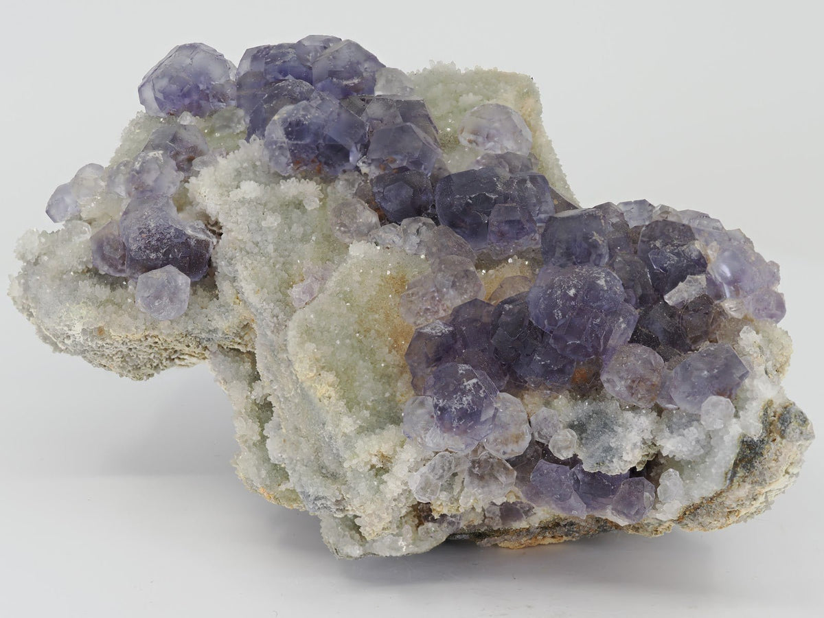 Cabinet sized Tanzanite Fluorite specimen from Fujian China featuring deep violet crystals on white drusy quartz.
