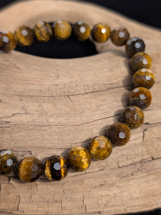 Macro close-up of 8mm faceted Tiger Eye beads catching the light and displaying fibrous banding.