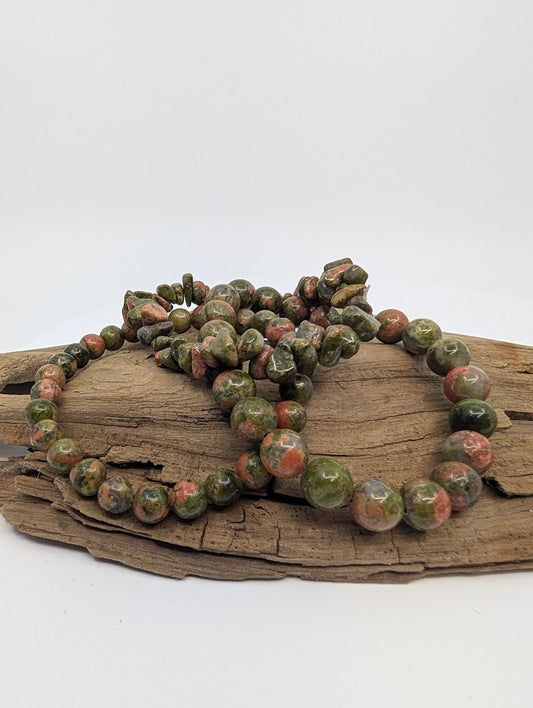 Unakite chip and round bead bracelets displayed on wood