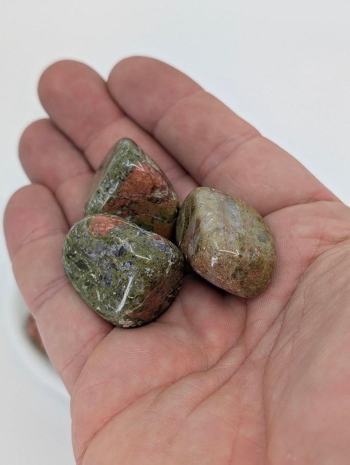 Hand holding Unakite tumbled stones showing polish and natural color blend