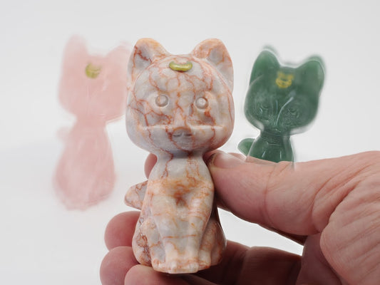 Close-up of a 3-inch Vein Jasper cat carving held in hand, showcasing natural red hematite vein patterns and gold moon inlay.