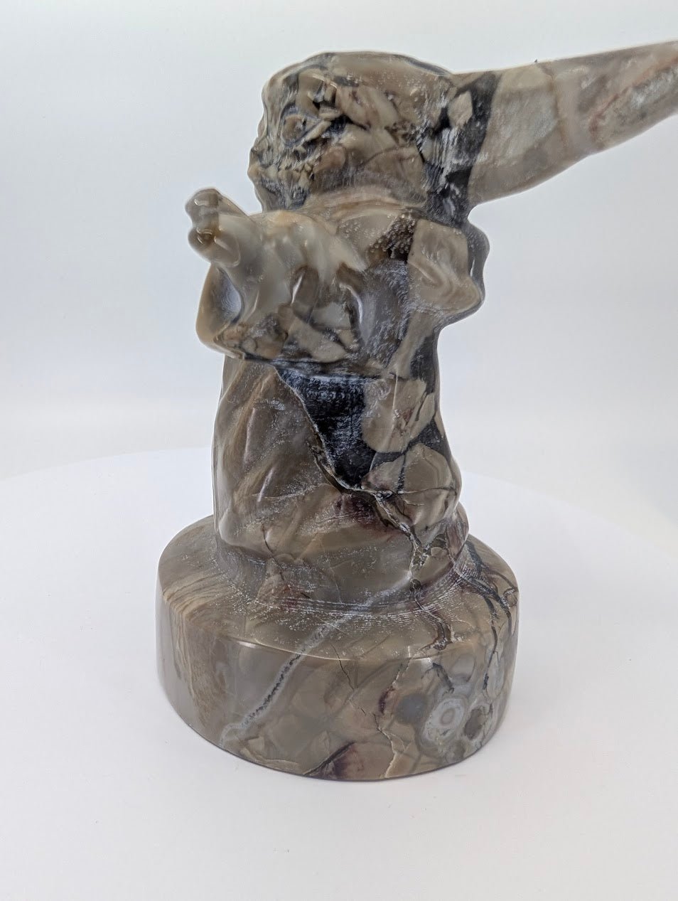 Right side view of polished volcano agate Gorgu figure on round base