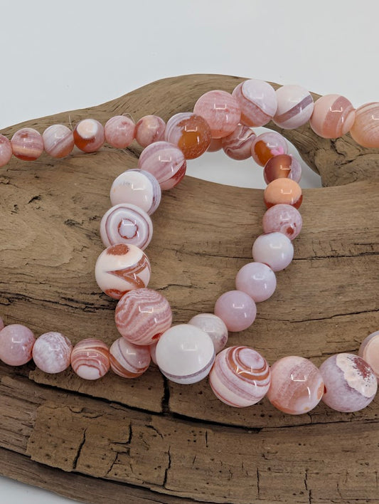 Close-up of Yancheng agate beads with swirling banded layers and peach tones