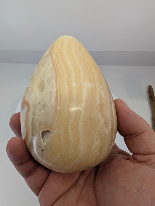 Hand-held view of a large yellow calcite egg showing size scale and natural surface texture