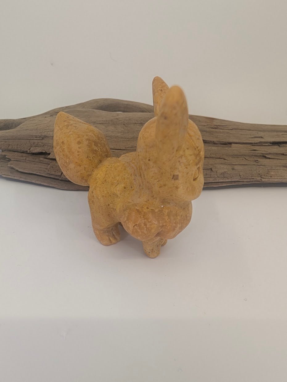 Side profile of an 80g hand-carved yellow jade Eevee, showing the intricate carving of the mane and large alert ears.