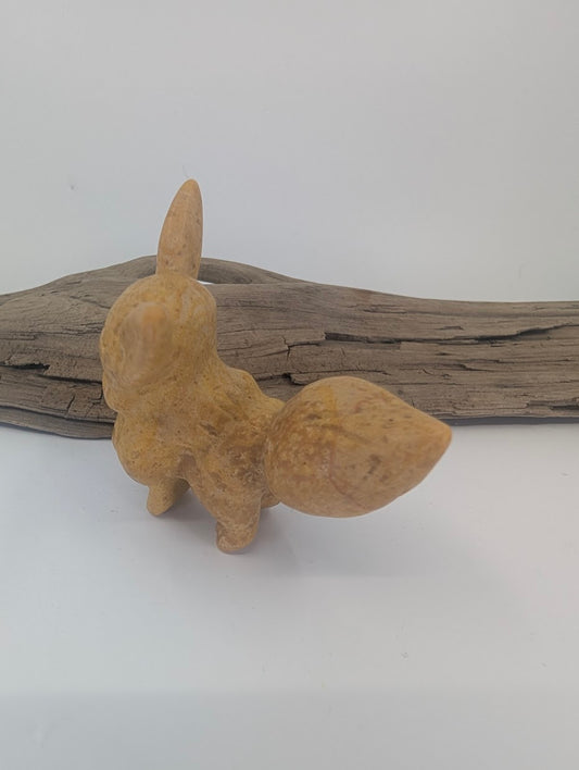 Rear view of a hand-carved yellow jade Eevee figurine, highlighting the detailed bushy tail and natural stone mottling.