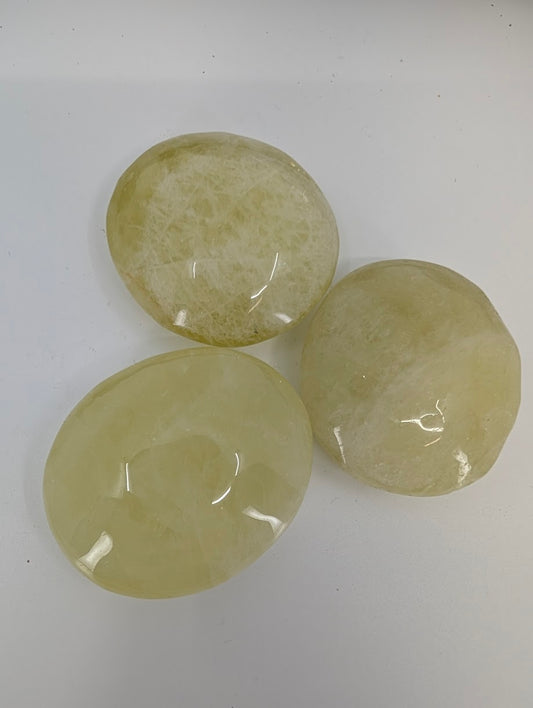 Group of yellow quartz palm stones showing natural color variation and polish