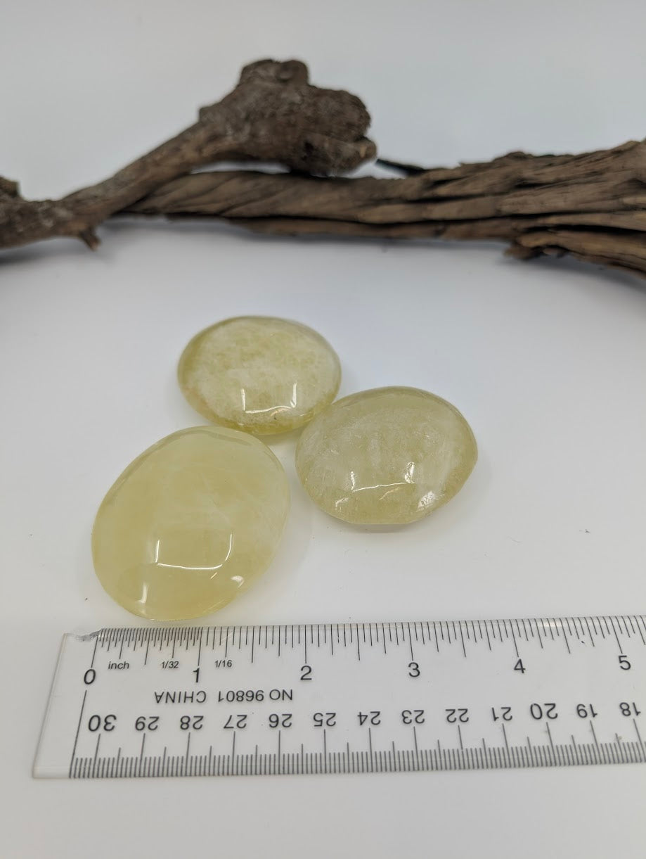 Yellow quartz palm stones beside ruler showing approximate size