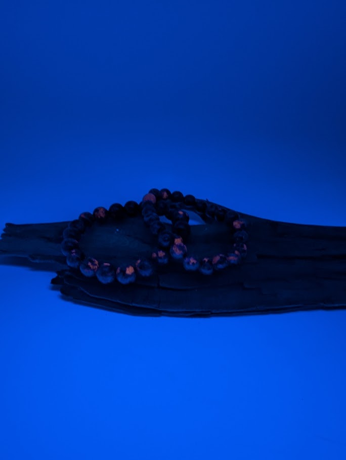 Detailed shot of Yooperlite beads glowing orange under UV Light