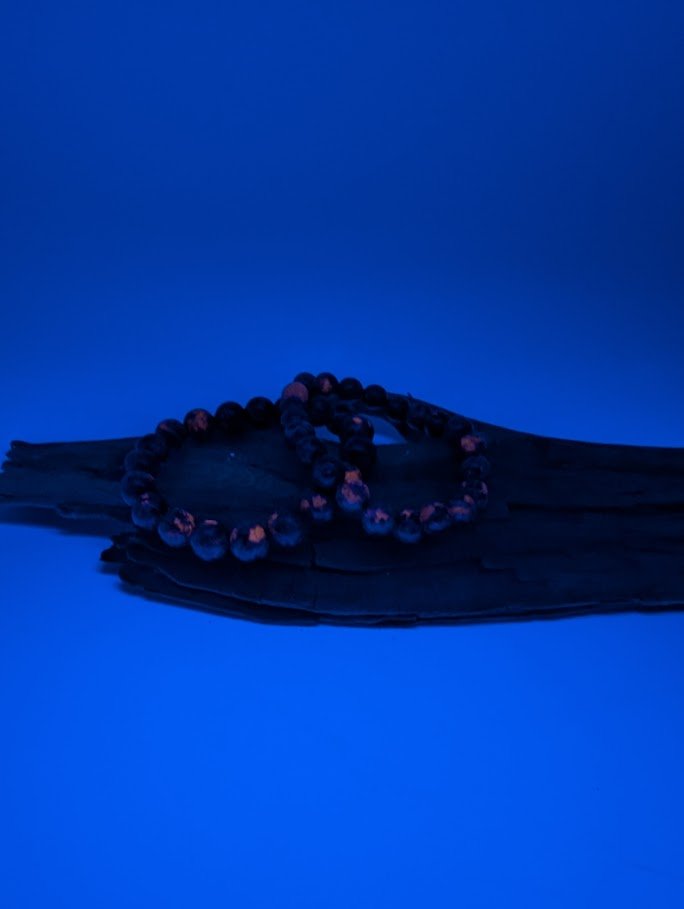 Detailed shot of Yooperlite beads glowing orange under UV Light