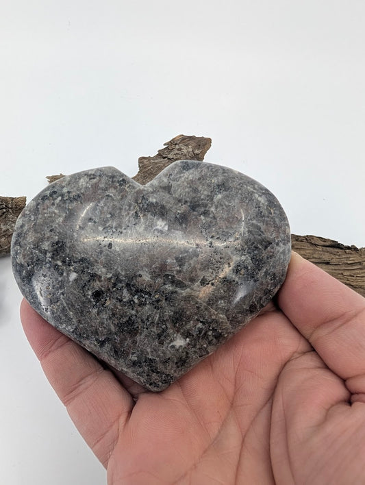 Hand holding a large 315g Yooperlite heart showing grey syenite texture.