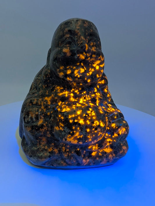 Yooperlite Laughing Buddha carving glowing bright orange under UV light